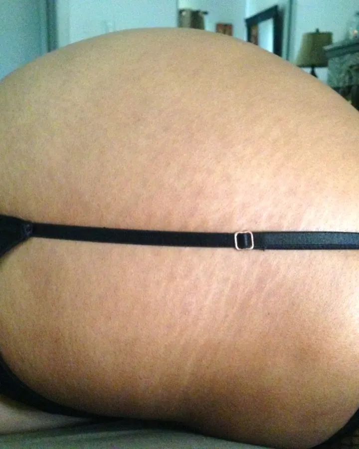 Photo en gros plan du derrière d'une femme en sous-vêtements noirs, avec un string et des collants résille.